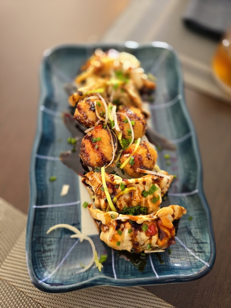 Croquetes e gyozas com molho e cebolinho num prato retangular azul do Koen Sushi