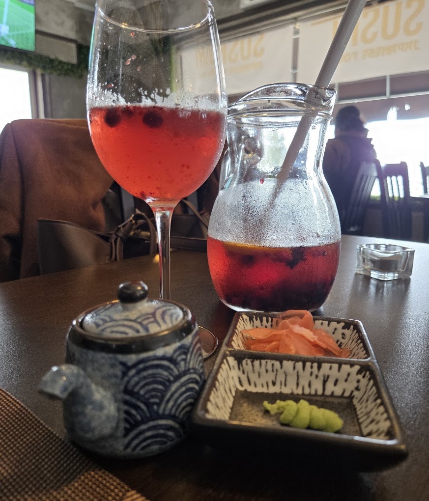 Jarro e copo de bebida com frutos vermelhos na mesa do Koen Sushi, com gengibre e wasabi